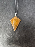 A triangular wooden pendant necklace with a silver-toned chain, displayed on a dark textured gray background.