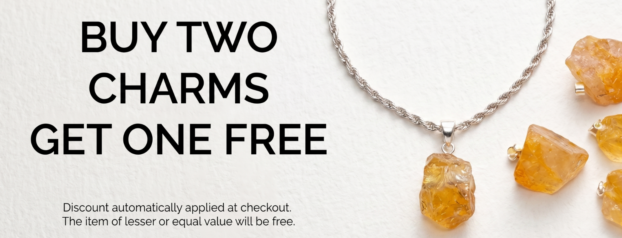 Promotional banner showing a silver chain necklace with a rough amber-orange charm, alongside several matching amber-orange charms, with text reading 'BUY TWO CHARMS GET ONE FREE' on a white background.