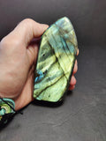 Hand holding a labradorite stone against a dark background