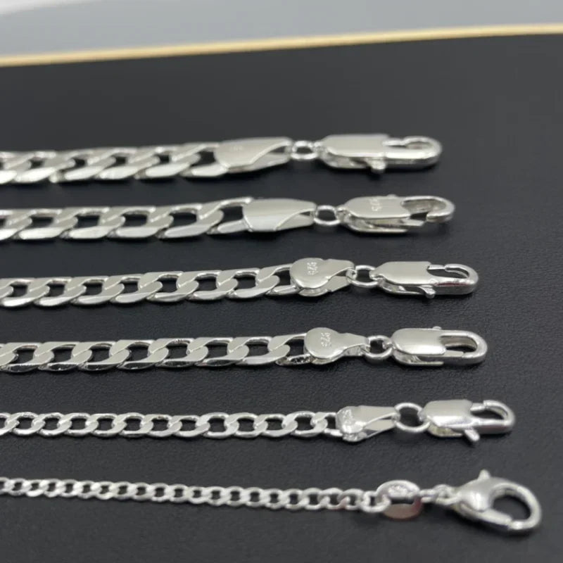 Set of silver chain necklaces on a dark surface